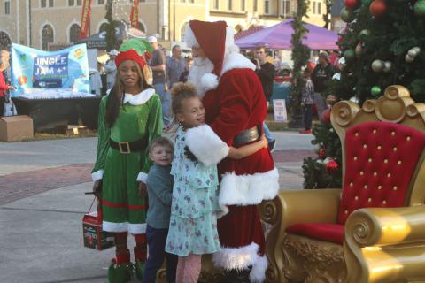 Santa Claus and one of his elves welcome a pair of children at the Christmas tree lighting  ceremony at Olustee Park Sunday night. (TONY BRITT/Lake City Reporter)