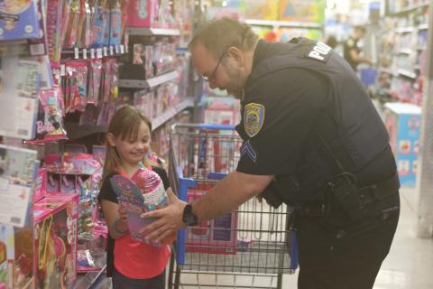 Paisley Daniels (left) is all smiles as she shows Lake City Police Department officer Brandon Rose an item she has selected for a Christmas gift, during LCPD’s Shop With A Cop event on Wednesday morning at Walmart. (TONY BRITT/Lake City Reporter)