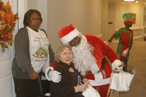 Trudie Johns gets a hug from Joseph Simmons, who portrayed Santa Claus on Sunday afternoon when members of the Our Community Cares Coalition visited residents at The Canopy at Harper Lake. (TONY BRITT/Lake City Reporter)