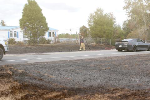 A Columbia County firefighter extends a hose as firefighters and law enforcement officers battled a brush fire Saturday afternoon on State Road 47 that jumped the road and threatened a home. (TONY BRITT/Lake City Reporter)