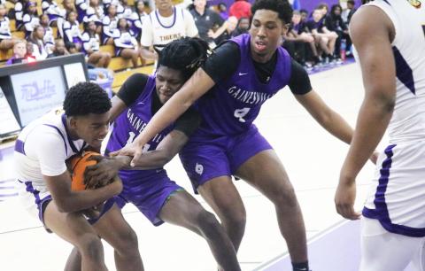 Columbia guard Murkail Cray gets tied up by Gainesville forward Craig Thomas (14) on Tuesday night. (JORDAN KROEGER/Lake City Reporter)