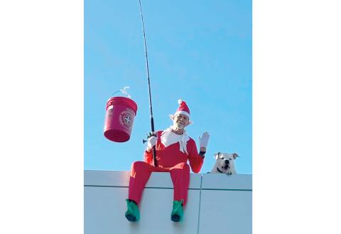 Rocky the Elf (Berry Raulerson) and Mann look out from the roof of Walt’s Live Oak Ford last weekend. (MONJA SLATER/Lake City Reporter)