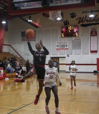 Fort White guard Isreal Hart goes for a layup past Baker County’s Kaitlyn Holland late in the fourth quarter of Tuesday’s win. (MORGAN MCMULLEN/Lake City Reporter)