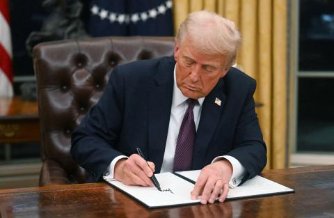 President Donald Trump signs an executive order in the Oval Office at the White House on Monday. One of the executive orders Trump signed either commuted the sentences or pardoned those involved with the Jan. 6, 2021, events at the Capitol. (JIM WATSON/AFP/Getty Images/TNS)