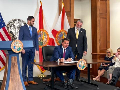 Florida House Speaker Daniel Perez and Senate President Ben Albritton watch Gov. Ron DeSantis sign legislation to address illegal immigration on Thursday. (LAWRENCE MOWER/Miami Herald/TNS)