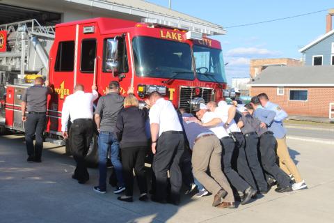 Members of the Lake City Fire Department push the department’s new tower truck into the Lake City Public Safety Building on Tuesday. The push-in ceremony is a traditional way to put new vehicles into service. (TONY BRITT/Lake City Reporter)