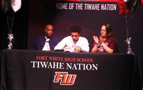 Fort White receiver Tafari Moe (center) signs his letter of intent to play football at Harvard University on Wednesday morning flanked by his parents, Russel (left) and Loretta (right). (MORGAN MCMULLEN/Lake City Reporter)