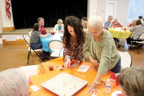Patti Kahlich (left) and her Scrabble partner Rene Keith, stand up to get a better vantage point while competing in last year’s Scrabble Tournament at the Club House on Lake Isabella. (FILE)