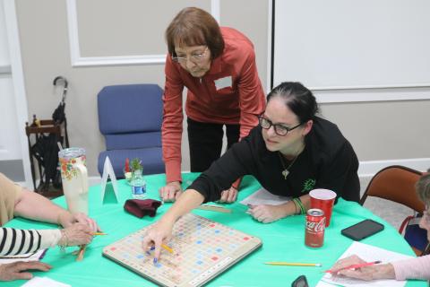 Linda Jansson (left) looks on as her Scrabble partner, Theresa DePasquaoe, places letter tiles on the Scrabble board during the championship round of the Lake City Garden Club’s Scrabble Tournament fundraiser. The pair won the tournament. (TONY BRITT/Lake City Reporter)