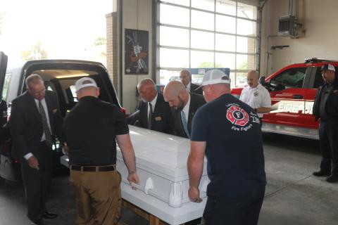 Lake City firefighters and members of Gateway-Forest Lawn Funeral Home pull a casket out of a hearse that the funeral home is donating to the department for training with the honor guard. (TONY BRITT/Lake City Reporter)