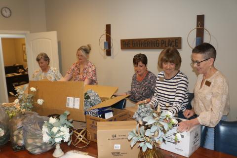 Donna Sandage (from left), Malynn Livingston, Vicki Morrell, Charlene Brown and Lori North open boxes of decorations that will be used for the Pregnancy Care Center’s 40th anniversary banquet, which will take place in a few weeks. (TONY BRITT/Lake City Reporter)