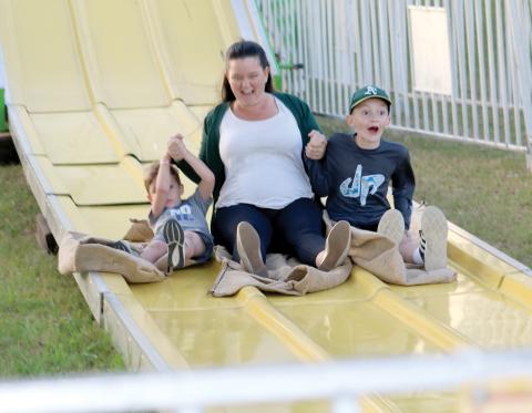 A woman and a pair of children enjoy their trip down a slide at a previous year’s Suwannee County Fair, which opens Friday and runs for nine days. (FILE)