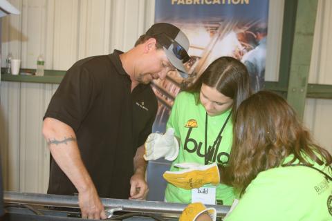 Gerard Gardner (clockwise from left), a New Millennium employee, shows Baker County High School students Mikayla Evans and Brooklyn Welsh how to work on building supports. (FILE)
