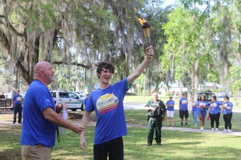 Columbia County Sheriff’s Office Sgt. Clint Dicks (left) looks on as Wyatt Kelly, of Lake City Christian Academy, proudly displays the torch moments before the annual Law Enforcement Torch Run for Special Olympics Florida on Tuesday morning. (TONY BRITT/Lake City Reporter)