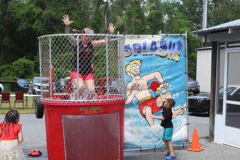 Seven Blumer falls in the water of the dunk tank on Saturday as an child presses the release mechanism. (TONY BRITT/Lake City Reporter)