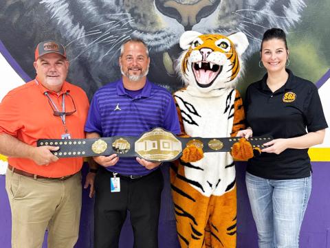 Columbia High Principal Trey Hosford (second from left), the school’s mascot and Student Government Director Tia Gainey accept the Florida Department of Transportation District 2 Battle of the Belts championship belt. (COURTESY)