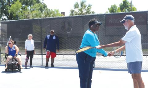 Stacy McCabe gets instructions on her backhand grip from Coach Mark Mansbach, as he teachers McCabe and other veterans the game of tennis through a local program. (TONY BRITT/Lake City Reporter)