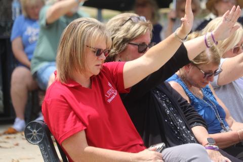 BillieJo Bible (from left), Donna Reese, Sue Tuell and Janet O’Connell raise their hands as they pray in Olustee Park during the National Day of Prayer event on Thursday afternoon. (TONY BRITT/Lake City Reporter)