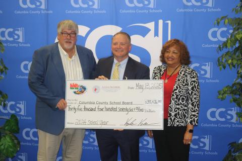 Columbia County Tax Collector Kyle Keen (middle) presents a $35,476 check to Superintendent Keith Couey and School Board Chair Narrie Smith as the proceeds from the Kids Tag Art program. (TONY BRITT/Lake City Reporter)
