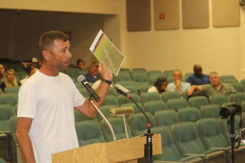 Bobby Griffis shows county commissioners a picture of damage to a local field during Thursday evening’s county commission meeting as several citizens attended the meeting opposing the plan to raise field usage fees for travel ball teams. (TONY BRITT/Lake City Reporter)