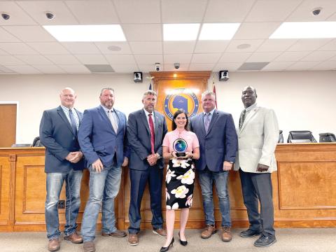 Suwannee County Economic Development Coordinator Charissa Setzer holds the ‘Innovation in Marketing’ award the county’s ‘We are Suwannee’ campaign earned at the Florida Economic Development Council conference last week. She is joined by commissioners Don Hale (From left), Leo Mobley, Travis Land, Franklin White and Maurice Perkins. (JAMIE WACHTER/Lake City Reporter)
