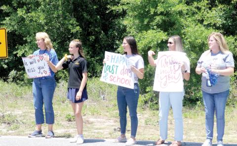 Eastside Elementary School faculty and staff members stand along SE Beech Street on Friday afternoon with signs, as students head home for summer vacation. Eastside Elementary School completed its last day of classes on Friday in the building that was opened in 1959. The building will will be demolished in a few weeks, making way for a new Eastside Elementary School. (TONY BRITT/Lake City Reporter)