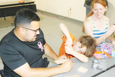 Columbia County School Resource Deputy Tony Geurra helps Negan Barker, 8, with his wood working skills. (TONY BRITTLake City Reporter)