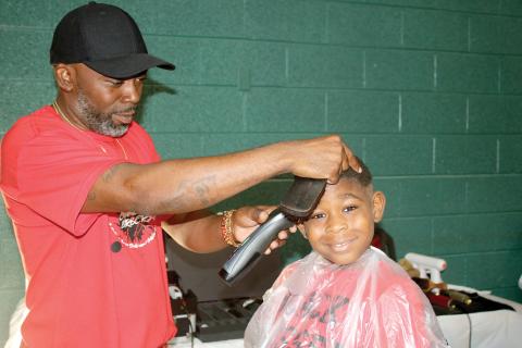 Tyrone Mullins, giving a haircut at a previous Community Barbers Back to School Bash, said this is a special year for the event as it marks its 10th anniversary. (FILE)