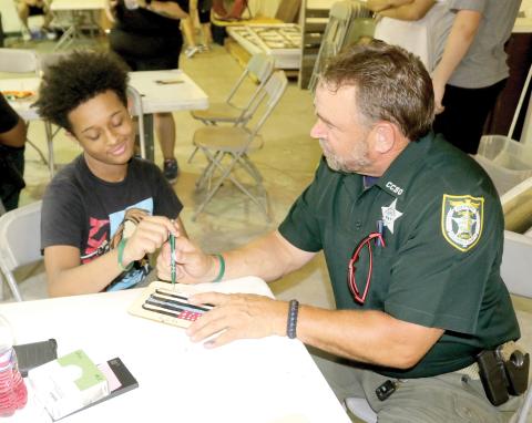 Darren Simmons (left), 13, gives his opinion to School Resource Deputy Scott ‘Chewy’ Ceckanowicz on his picture frame. (TONY BRITT/Lake City Reporter)