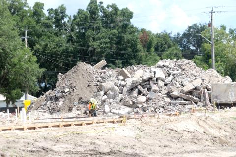 A construction worker looks at some concrete slabs that have been poured on the Eastside Elementary School campus Wednesday as a mountain of debris from the previous school is piled up behind him. (TONY BRITT/Lake City Reporter)