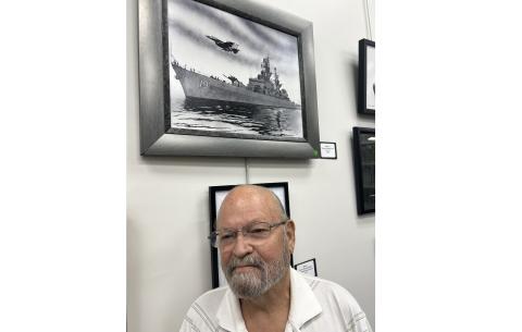 Benjamin Ragland poses in front of his winning drawing of the USS Dale with an F14 Tomcat flying overhead.