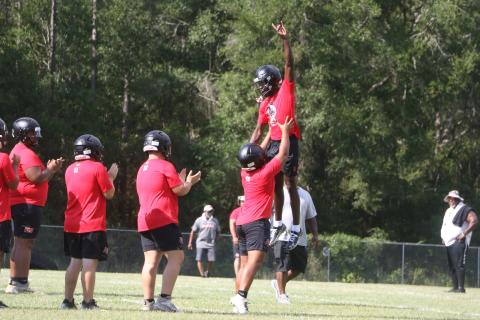 Fort White quarterback Jayden Jackson is hoisted to the air by left tackle Tayvin Fleming ahead of Monday’s practice. (MORGAN MCMULLEN/Lake City Reporter)