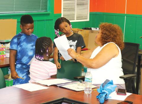 Narrie Smith, a retired Columbia County School District educator, helps children with their homework while they are at the NorthStar Family Resource Center on Tuesday afternoon. (TONY BRITT/Lake City Reporter)