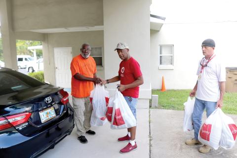 Bernard George (from left), brings bags of donations for displaced fire victims to American Red Cross workers Darryl Crawford and Doug Silvey on Thursday afternoon. (TONY BRITT/Lake City Reporter)