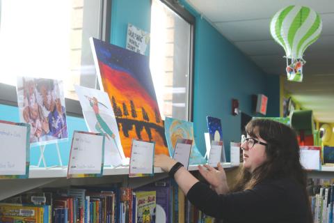 Columbia County Public Library Programming Specialist Emma Chieuw arranges art pieces ahead of the library's 2025 Youth Art Contest. (TONY BRITT/Lake City Reporter)