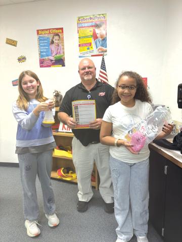 Charlie Stermer (from left) holds a LifeVac Airway Clearance Device while  standing with Ed Carter, Fort White Elementary School principal, and Aubrie Brown, holds a bag with another of the devices. (COURTESY)