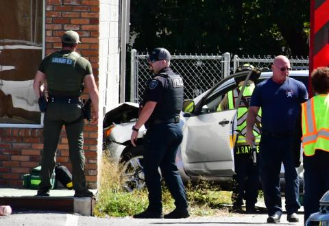 Law enforcement and first responders look on Sunday afternoon after a car crashed into the side of Carroll’s Laundromat on Ohio Avenue South. (ROB WOLFE/Lake City Reporter)