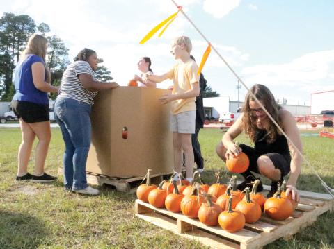 Ryan Pursel arranges pumpkins on a pallet at the Columbia High School Pumpkin Patch. Local FFA students are trying to sell the 1,502 pumpkins as a fundraiser. (TONY BRITT/Lake City Reporter)