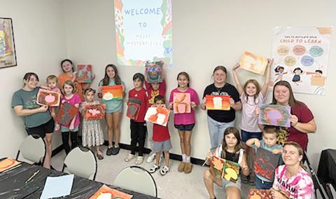 Participants in the first ‘Messy Masterpieces’ class at the West Branch Library show off their artwork Saturday. (COURTESY)