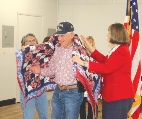 Anthony R. Hare (center) has a quilt of valor draped across his shoulders during the American Legion Post 57 Veterans Day program on Tuesday. (TONY BRITT/Lake City Reporter)