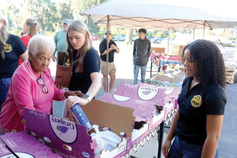 Catholic Charities volunteers Carrie Alexander (clockwise from left), Madeline Moore and Amani Tunsil add items to boxes that were given to local families for the annual Catholic Charities Thanksgiving Basket giveaway, which was held Thursday. (TONY BRITT/Lake City Reporter)
