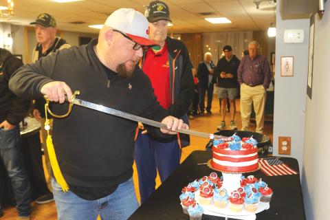Kyle Warner, keynote speaker for the Lake City Elks Lodge #893 Marine Corps 250 birthday celebration, uses a sword to cut the birthday cake for the event. (TONY BRITT/Lake City Reporter)
