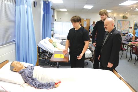 Fort White High School Health Occupation Science Academy students Jack Schroader (from left) and Christopher Meagher explain how they conduct a patient examination to FEA President Andrew Spar, who visited the school on a tour Tuesday afternoon. (TONY BRITT/Lake City Reporter)