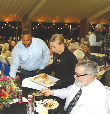 Weslyn Feagle (center) provides lasagna and garlic knots for Columbia County Commissioner Kevin Parnell (left) and County Manager David Kraus during Thursday night’s Farm to Table event at Darby Pavilion. (TONY BRITT/Lake City Reporter)