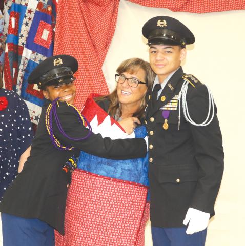 First Sgt. Trena Dettmer, Columbia High School JROTC instructor, is hugged by students after she received a Quilt of Valor from the Lady of the Lake Quilters Guild on Wednesday morning. (TONY BRITT/Lake City Reporter)