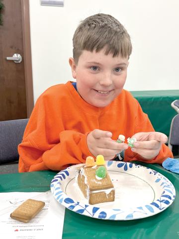 Donovan Corbett shows off some additions to his gingerbread house as he continued to work Monday during the 4-H STEM Explorers Club’s Christmas meeting. (COURTESY)