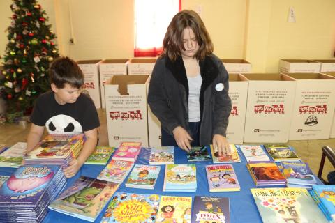 Phury Hunlock (left), 10, and Piper Hunlock, 13, volunteer their time arranging books that will be given as Toys for Tots Christmas gifts. (TONY BRITT/Lake City Reporter)