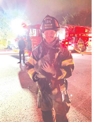 A Lake City firefighter holds Chase after the dog was  rescued from a house fire Monday. (COURTESY)