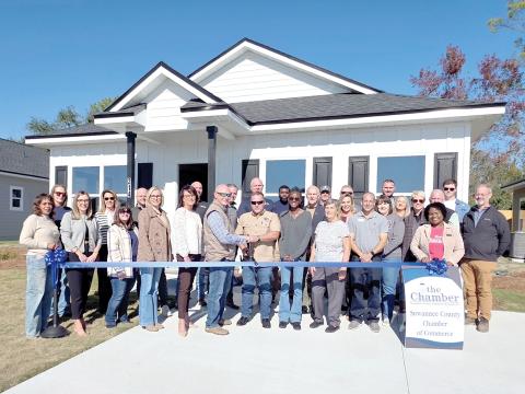 Milton Smith and Darren Webb with GSMS Developers cut the ribbon in front of one of the new houses in the Canyon Vistas subdivision in Live Oak. GSMS evelopers was joined at the ribbon cutting by Suwannee County Chamber of Commerce represenatatives as well as Suwannee County and City of Live Oak officials. (MONJA SLATER/Lake City Reporter)
