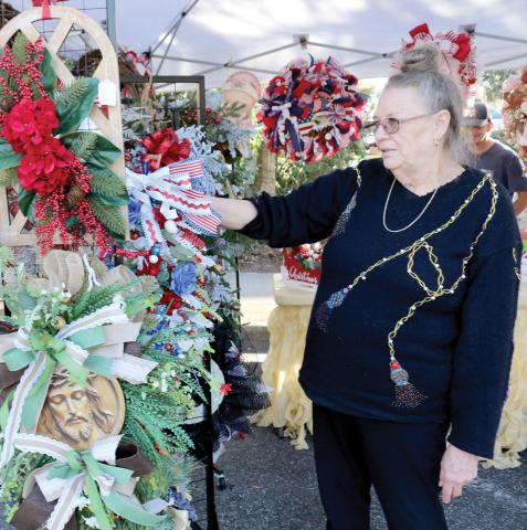 Deborah Water of Fort White, a vendor in the local holiday market, organizes Christmas wreaths in her booth. (TONY BRITT/Lake City Reporter)